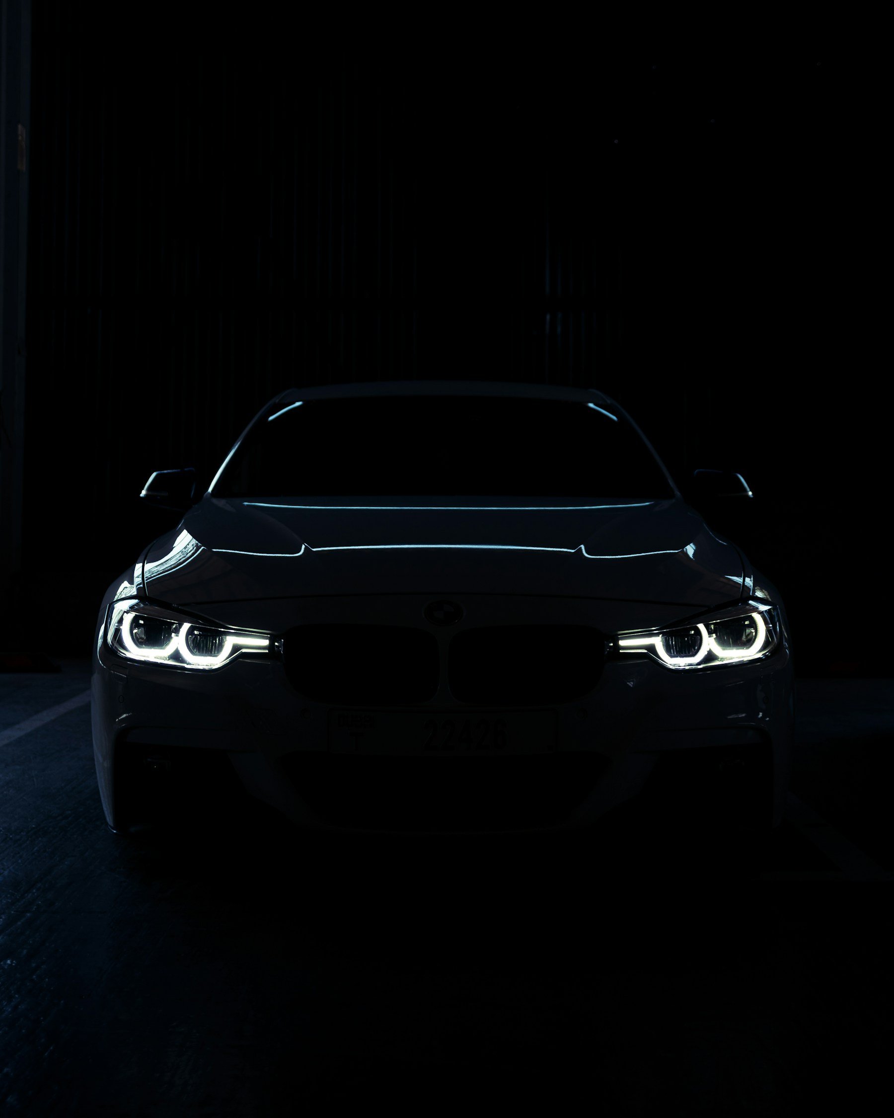 Editorial photograph of illuminated headlights on a car in darkness